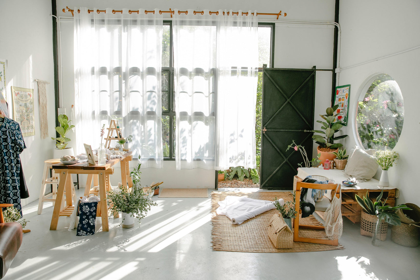 Light filled room full of plants and wood made items.
